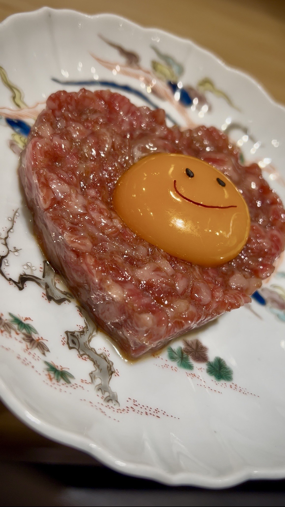 笑顔を描いた卵黄を添えた和牛ユッケ